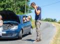 A man calls for help next to a broken down car. Picture by Shutterstock