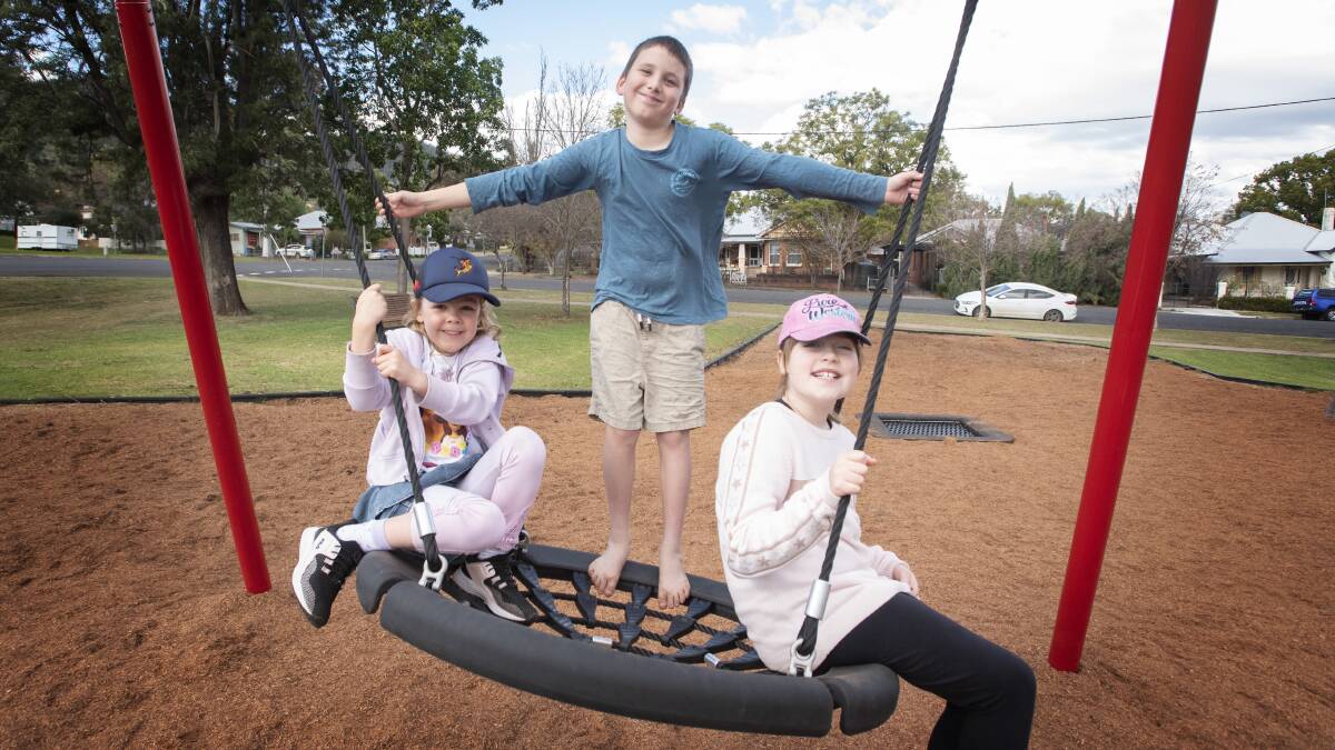 In the swing: Piper Nell, Dante Ridoux and Portia Nell enjoy new play equipment at Anzac park. Photo: Peter Hardin 030720PHE005