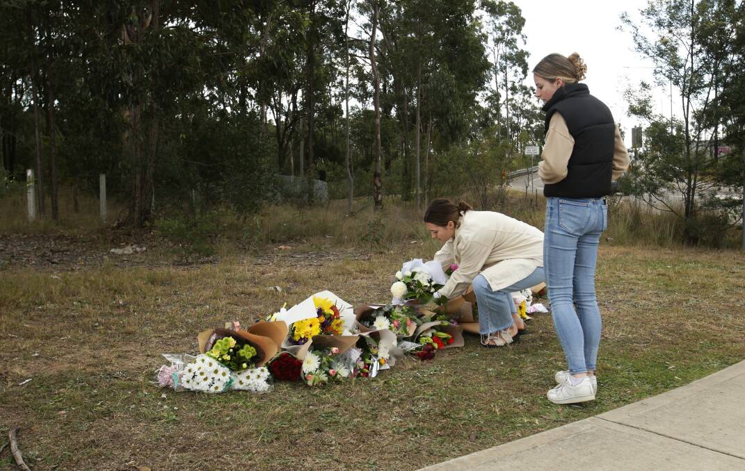 People place flowers on behalf of Cessnock Ambulance down from the site of the bus crash on Wine Country Drive. Picture by Simone De Peak