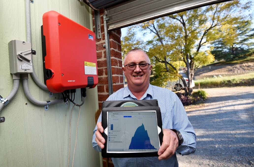 BRIGHT IDEA: Jim Booth with his solar system (the red box). An app that comes with the system gives him an hourly update about how energy the solar panels generate. Photo: Gareth Gardner
