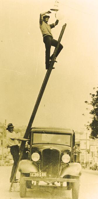 HELPING HAND: Sid Cross changing a lamp on a street light fitting in 1933, with Jack Perfrement steadying the ladder. Photo: Powerstation Museum Collection