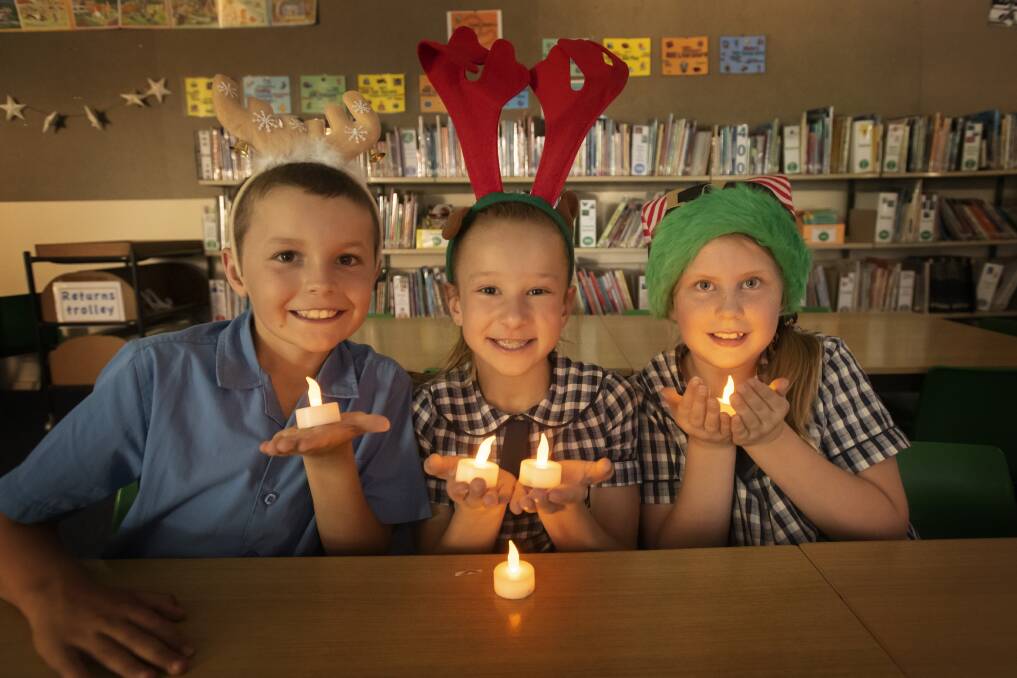 BY CANDLE LIGHT: Timbumburi students Daniel Rushbrook, Kallie Griffiths and Bonnie Kendall get in to the Christmas spirit. Photo: Peter Hardin