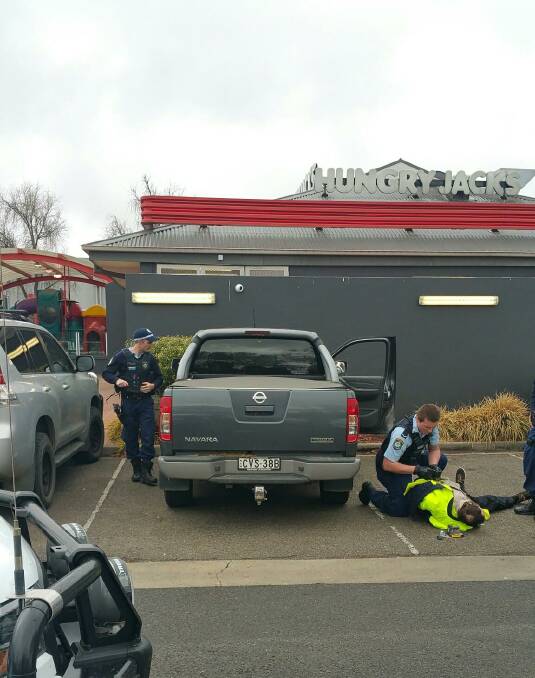 On the ground: Armidale police arrest a man in the carpark near Hungry Jacks. Photo: Supplied