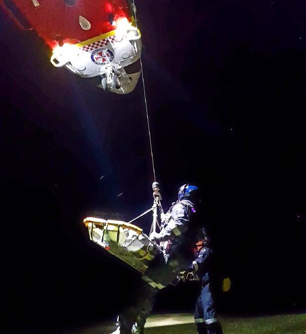 Rescue: The crew from the Westpac Rescue Helicopter winch the injured bushwalker out of the Blue Hole on Sunday night. Photo: Westpac Rescue Helicopter