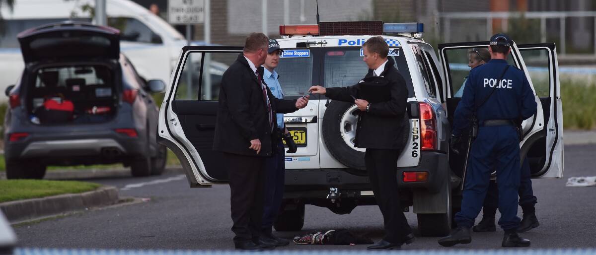 IN CUSTODY: Investigators surround the police vehicle were a man was detained for questioning over an alleged stabbing attack in Coledale. Photo: Gareth Gardner 170816GGC09