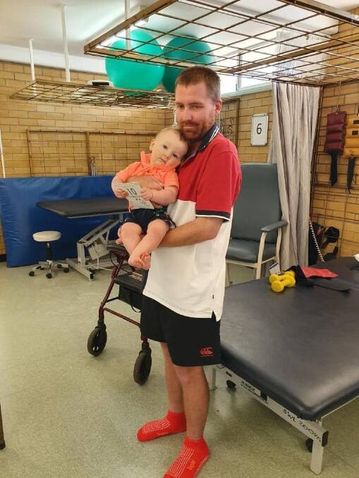 Red, holding Ollie, has improved since last week when he was unable to balance and stand without holding onto something. Photo: Andrea McClymont
