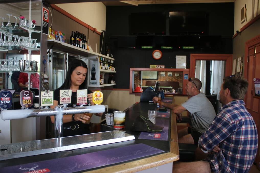 OUT OF WORK: Canadian backpacker Courtney serving in the Curlewis pub before it closed due to federal government laws. She and her friend Rachel are still living at the pub, thanks to the generosity of its owners. 