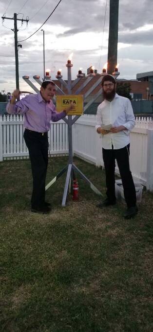LIGHT IN DARKNESS: Eddie Whitham with the region's Rabbi Menachem Aron lighting the sixth candle for the Jewish festival of Hanukkah with a small gathering in Tamworth. Photo: Supplied