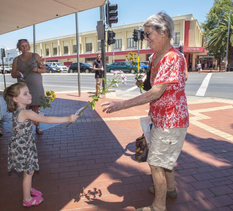 Chantelle Sims watches as her daughter Laura, 4, gives flowers to Peggy Scott in the Tamworth CBD. Photo: Peter Hardin 231216PHD011