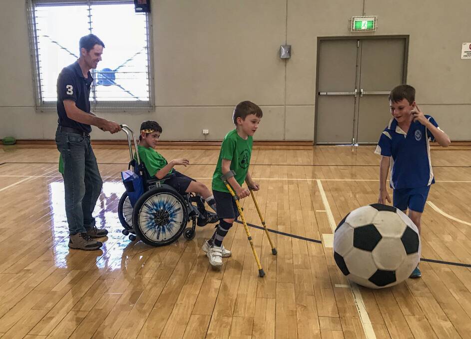 FUN FOR ALL: James Filby pushes Lachlan, while Timmy Wark and Hamish Filby go for the ball, at a Wheels and Walkers Family Sports Group session.