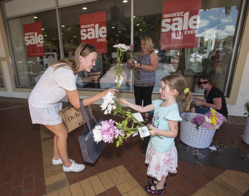 SURPRISE: Josie Wilson, 5, gives a flower to Kate Farquhar in the Tamworth CBD this afternoon, while Teresa McMullen and Marg Wilson wait for their next recipient. Photo: Peter Hardin 231216PHD001