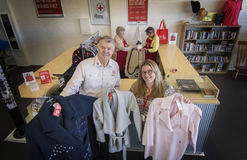 STEALS: Red Cross youth and community programs officer Stephen Riley and Red Cross area manager Tracie Walters show off some of the stock in the new shop, while Shirley Bell and Robyn Clapham steam a garment in the background. Photo: Peter Hardin 300818PHC015