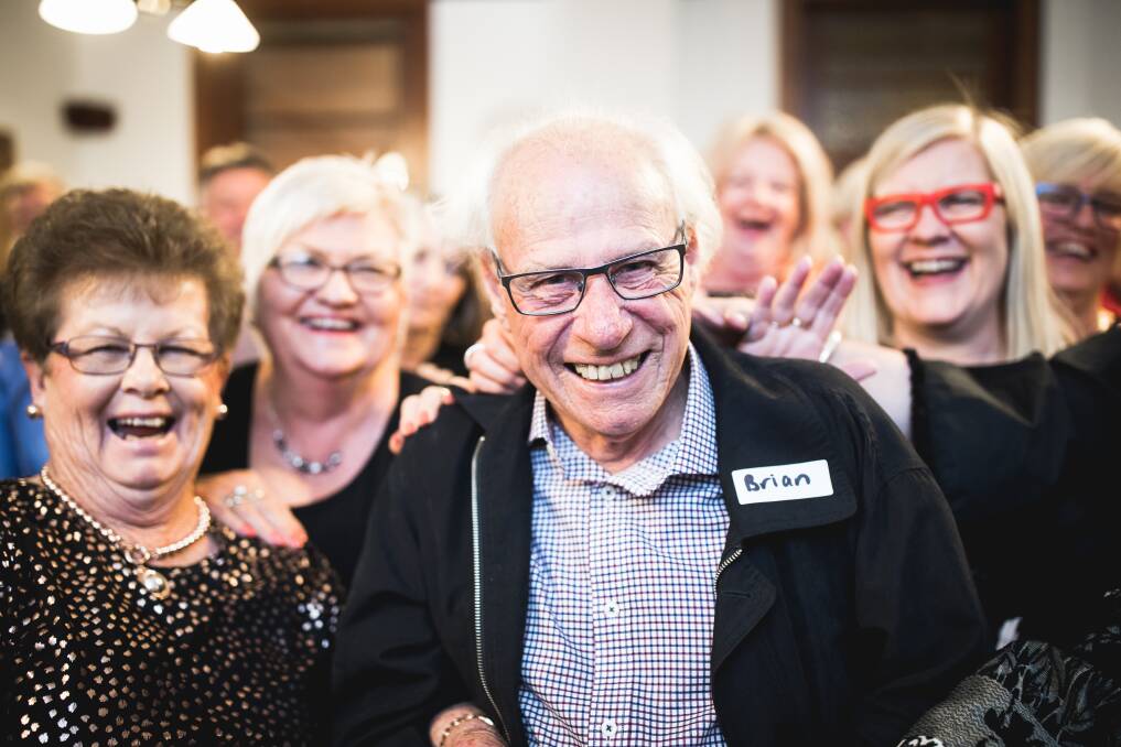 Brian Condon surrounded by his former staffers and now friends. Note the humorous touch of making the guest of honour wear a name tag! Photo: Andrew Pearson Photography