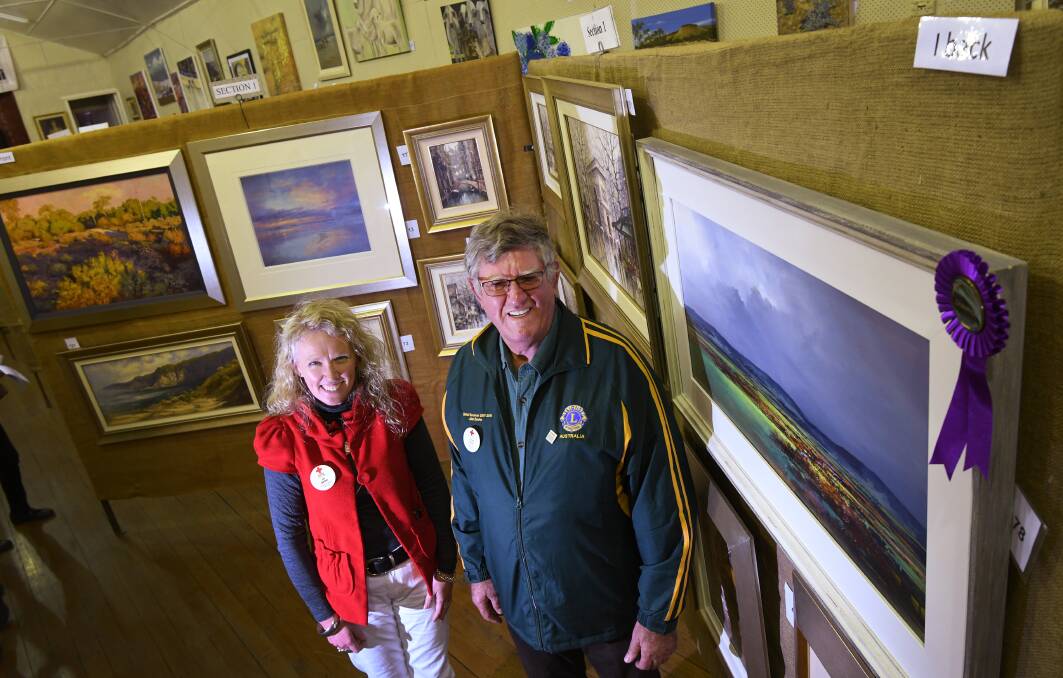 VOLUNTEERS: Local Red Cross branch committee members Jo Barr and John Davis with the champion painting. Photo: Gareth Gardner 180518GGF001