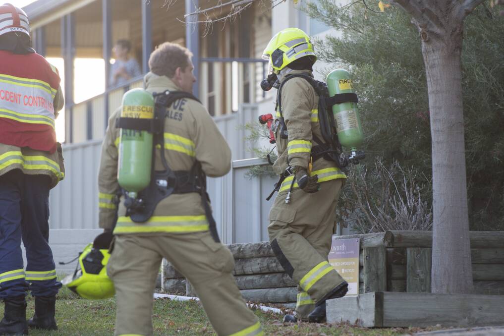 Two firefighters exit the premises after bringing the fire under control. Photo: Peter Hardin