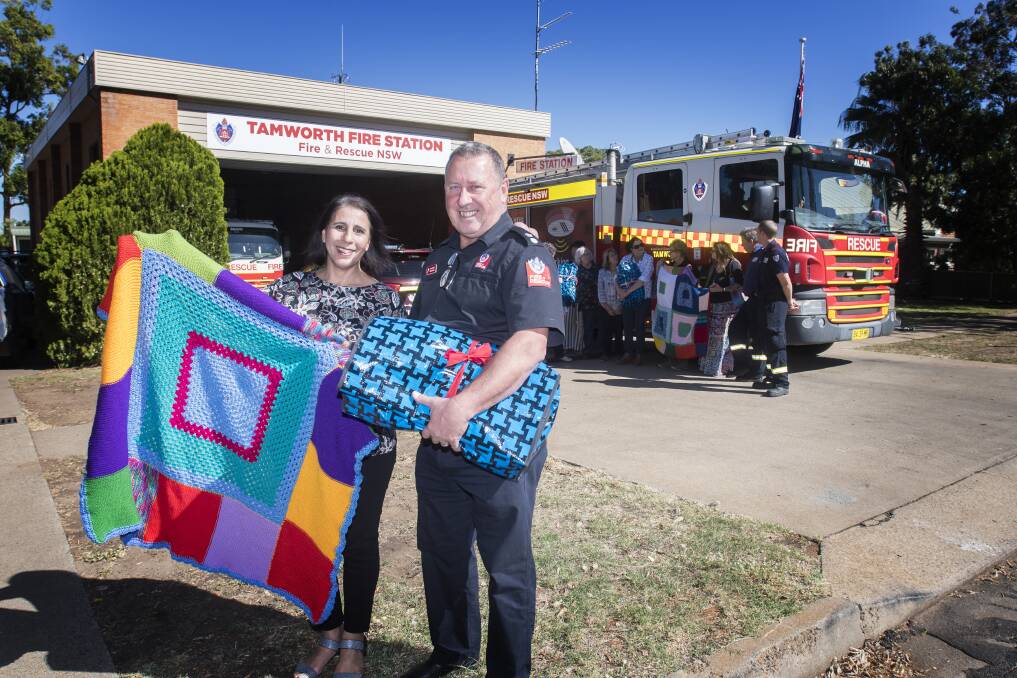 Heart warmer: Josie Coyle gives the first of many hand-knitted blankets to Fire and Rescue NSW Superintendent Tom Cooper. Photo: Peter Hardin 290419