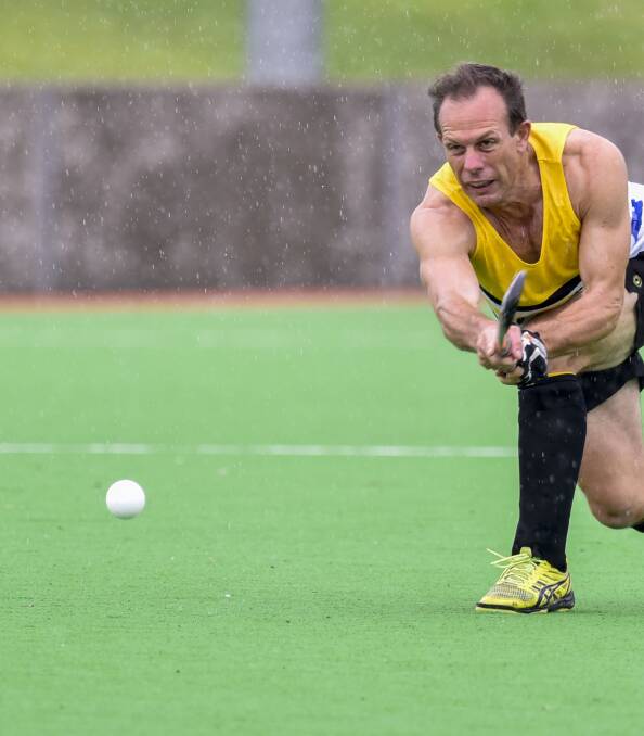 Eight straight: Andrew Farmilo flicks a long ball to support as the rain continued to come down on the men's final with Services Workies' winning dynasty stretching to eight titles.