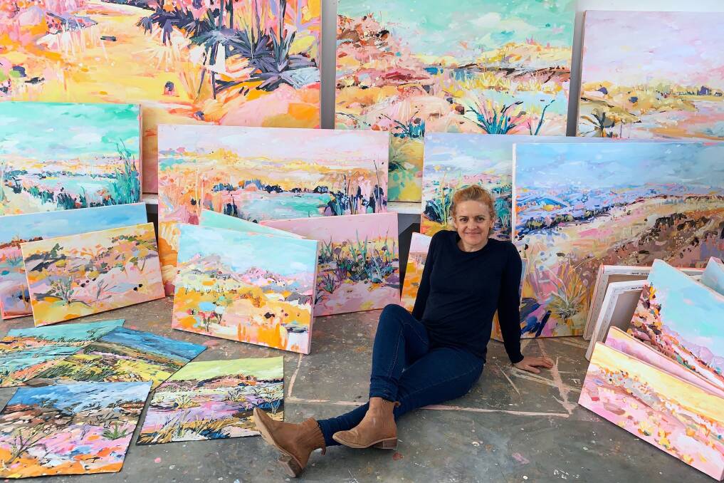 UPLIFTING: Paula Jenkins in the studio with her Riverbeds & Spinifex paintings. Photo: Supplied