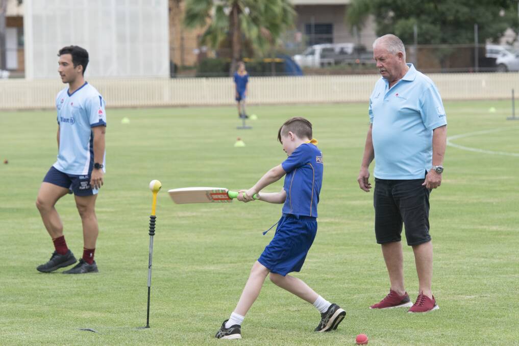 YOUNG GUN: This junior player has a blast at the Baggy Blues coaching clinic at No 1 Oval, as Steve Rixon looks on. Photo: Peter Hardin