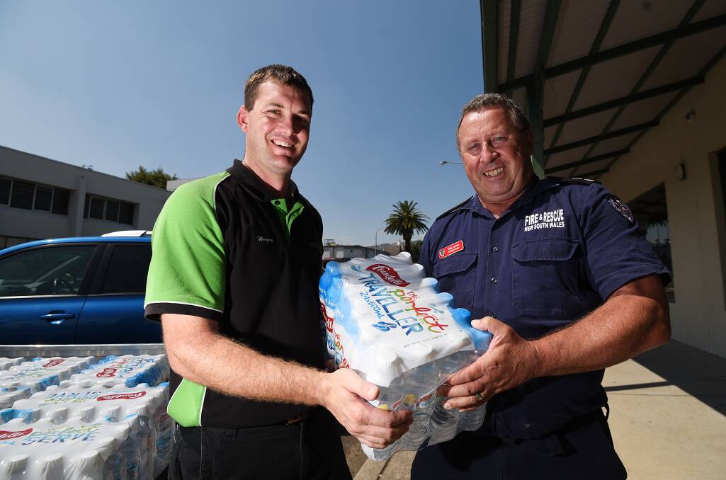 THANKS: Wayne Wall donates bottles of water to Fire & Rescue Superintendent Tom Cooper on behalf of Mick Pearson Pest Solutions as local crews help battle blazes across the state. Photo: Gareth Gardner 130217GGE01