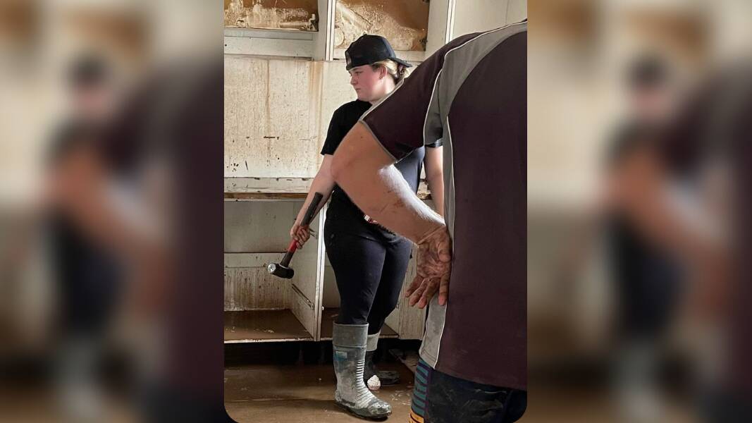 Zone 1 Young Woman of the year Jenna Robinson takes a hammer to her kitchen after record floods in South Lismore rose to the ceiling. Photo: Supplied