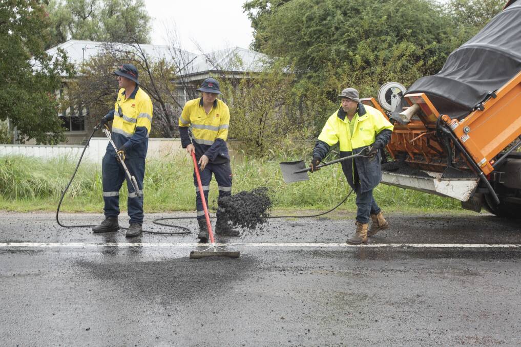 AT WORK: Traffic NSW crews braved the rain to fill in potholes on the highway caused by the wet weather. Photo: Peter Hardin