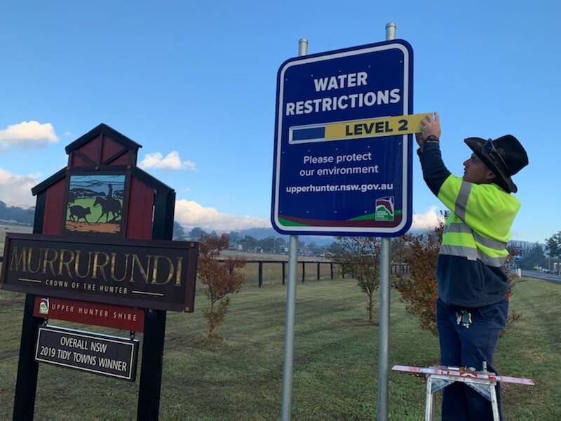 SWEET RELIEF: Upper Hunter Shire Council staff change the Level 6 water restrictions sign over to Level 2 after the opening of a new pipeline at Murrurundi. Photo: UHSC
