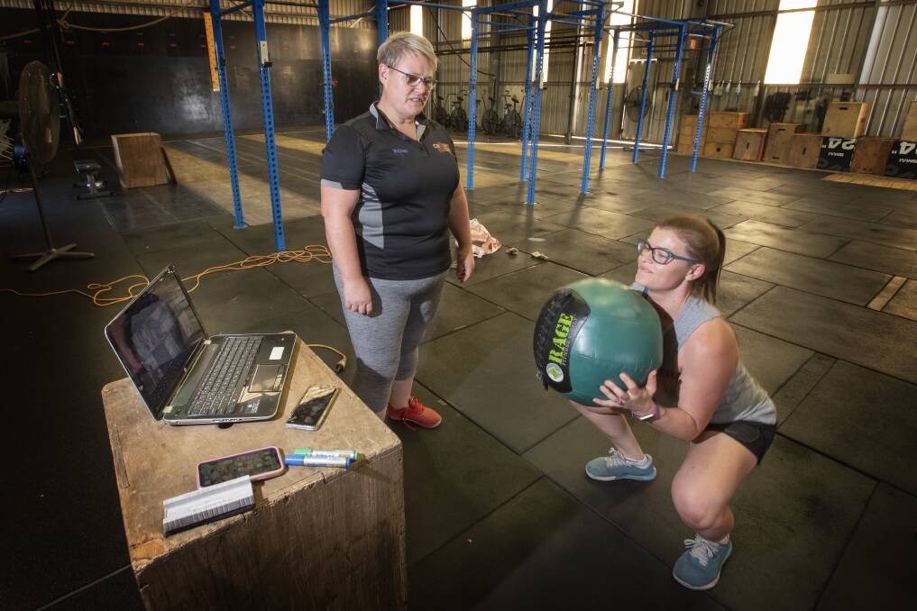 SQUAT GOALS: Kim McLean and Veronica Pearson from CrossFit 2340 have quickly adapted to new government restrictions by taking their training online. Photo: Peter Hardin 240320PHH026