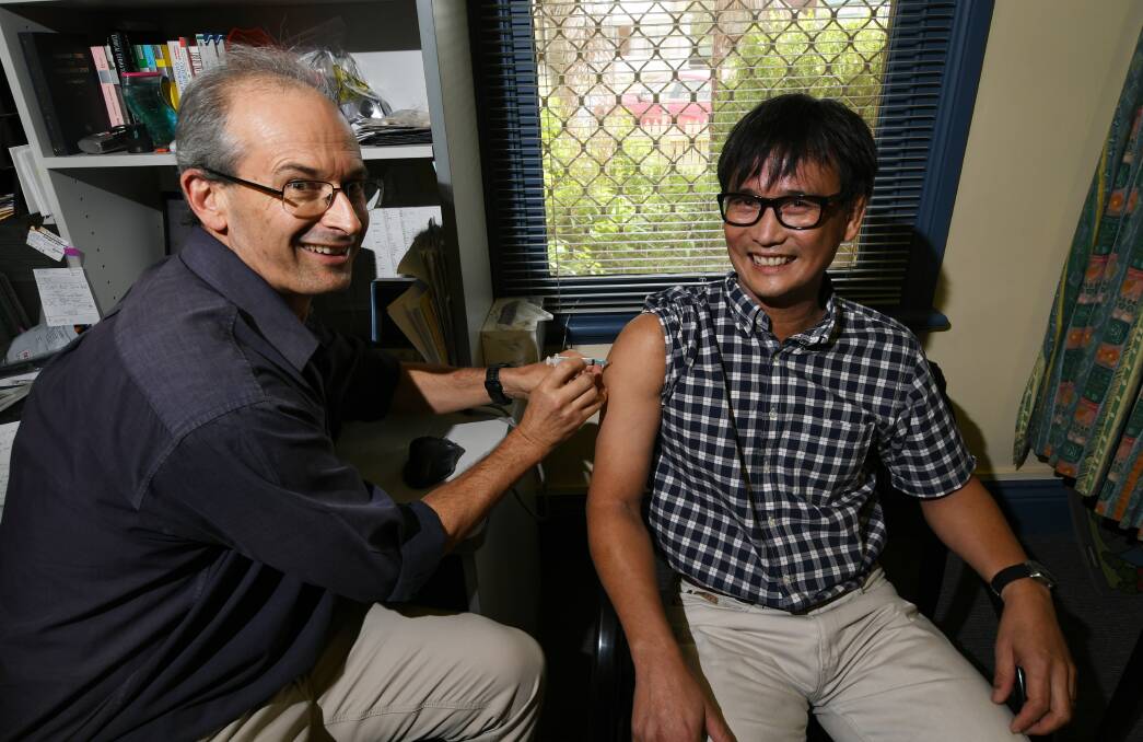 GIFT OF JAB: Dr Jim Stacey gives the vaccine to Dr Chris Fay at The Belmore Surgery in Tamworth, as eligible locals flock to book appointments. Photo: Gareth Gardner 