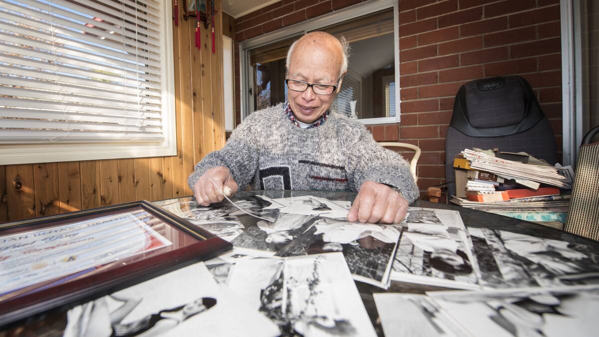 REFLECTIONS: Paul Ying looks through old photographs of his daughter Sze Ming he took on an old film camera. Photo: Peter Hardin 210619PHC028