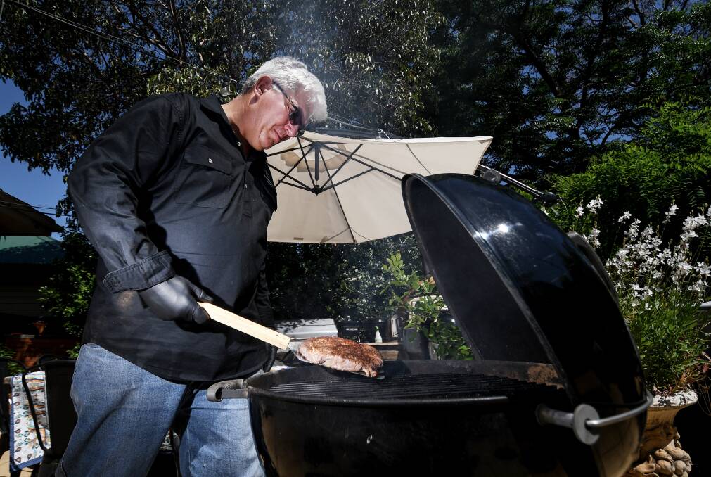 SMOKIN': Tamworth BBQ Man Pete Bukowski perfectly grills a steak on one of his fourteen barbecues in the backyard. Photo: Gareth Gardner