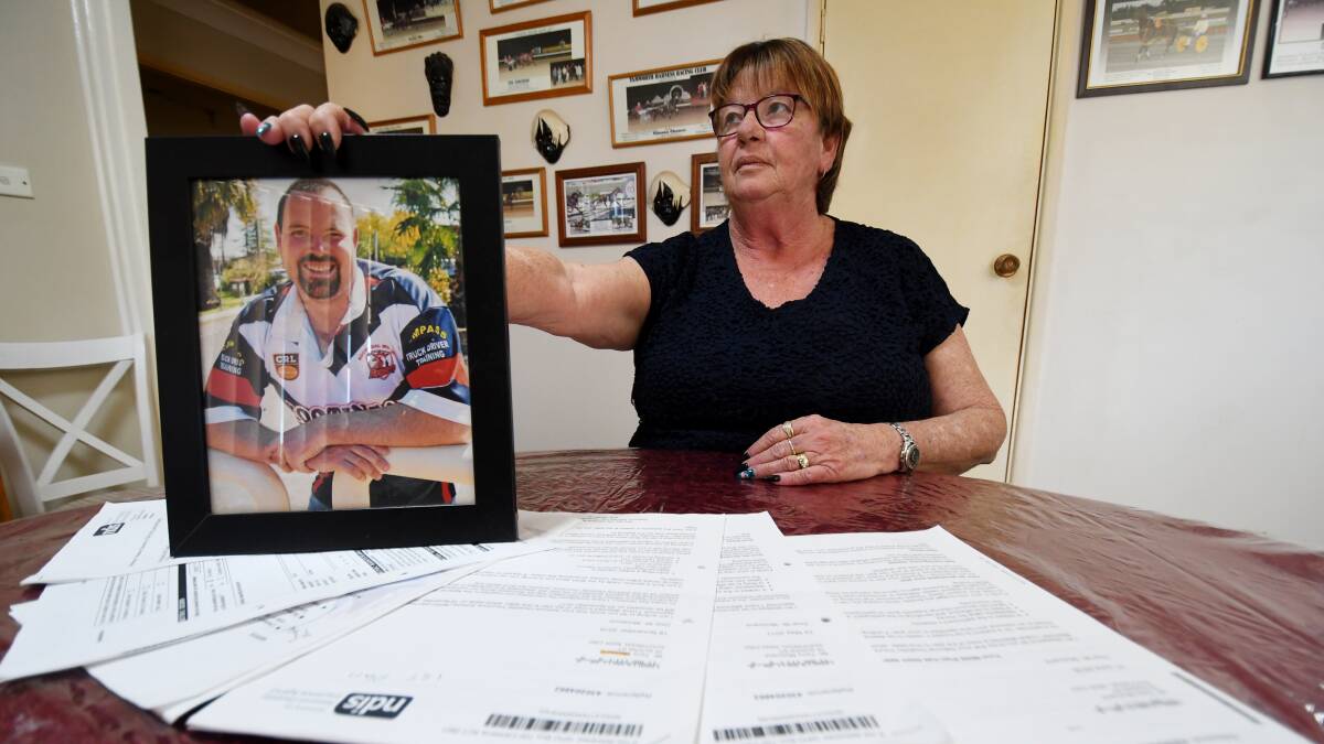 UNIMPRESSED: Kootingal mother Shirley McCluand holds a photo of her son Terry, who has cerebral palsy at a table with all of her correspondence with the NDIS to secure an appropriate plan for her son. Photo: Gareth Gardner