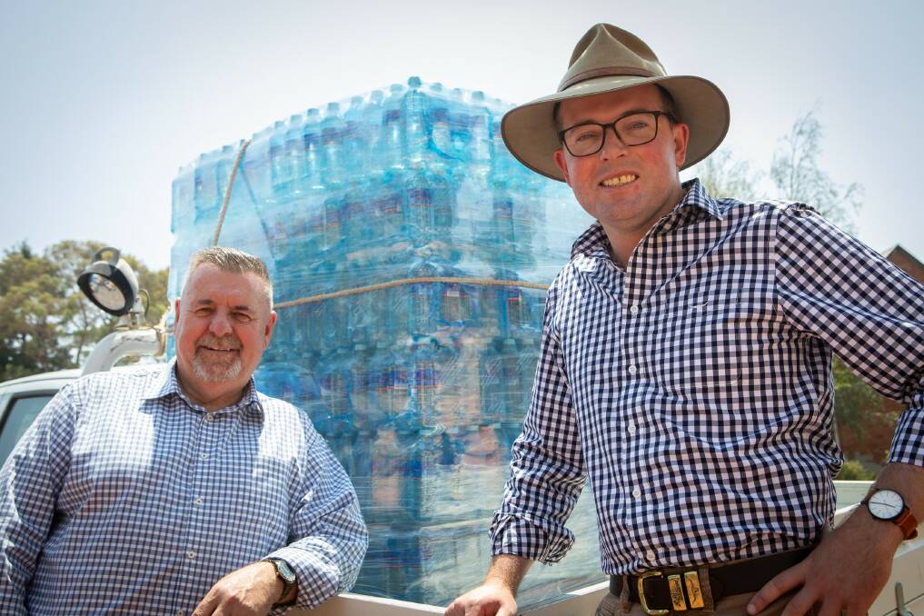 Northern Tablelands MP Adam Marshall, right, and Uralla Shire Mayor Mick Pearce with one of the hundreds of pallets of bottled water being delivered to Uralla residents.