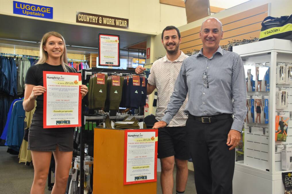 The Premier Store's Erika Lonergan, Joe Ferris and David Ferris stand by the woollen sock collection bin and Humphreys Law Australian-made sock stand in Inverell.