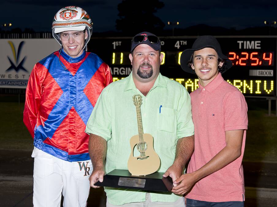 'Terrific feeling': Reinsman Will Rixon, owner Scott Whitton and son Matthew show off the coveted Golden Guitar trophy after Aqua Sancta won the $40,000 feature on Friday night. Photo: PeterMac Photography