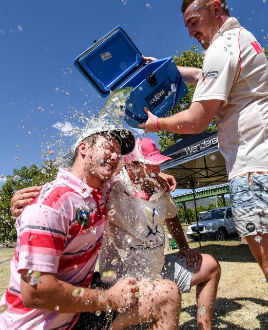 Cooling off: Kyle Nicholls provides some relief from the heat to Old Boys captain Brad Walters and Wests captain Ben Schubach during West's Pink Stumps Day on Saturday. Photo: Gareth Gardner 110217GGD02