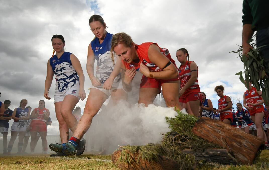 Swans women's midfielder Jess Hall leads the players through the 'cleansing' smoke as part of Saturday's Indigenous round. Photo: Gareth Gardner