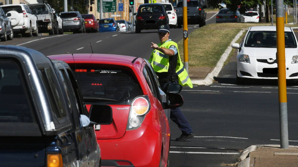 OVER AND OUT: A police officer directs motorists before traffic controllers arrive at the Brisbane Street intersection on Friday afternoon. Photo: Gareth Gardner