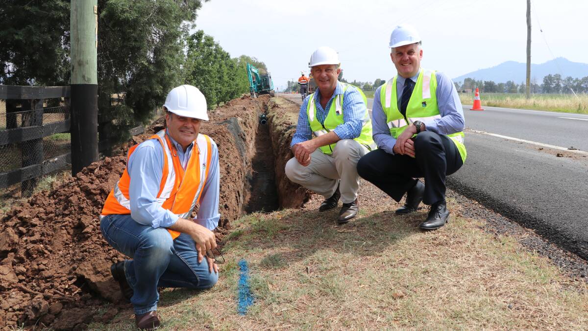 DIGGING IN: Mayor Wayne Bedggood, Upper Hunter MP Michael Johnsen and council general manager Steve McDonald inspecting the pipeline beside the New England Highway. Photo: Supplied