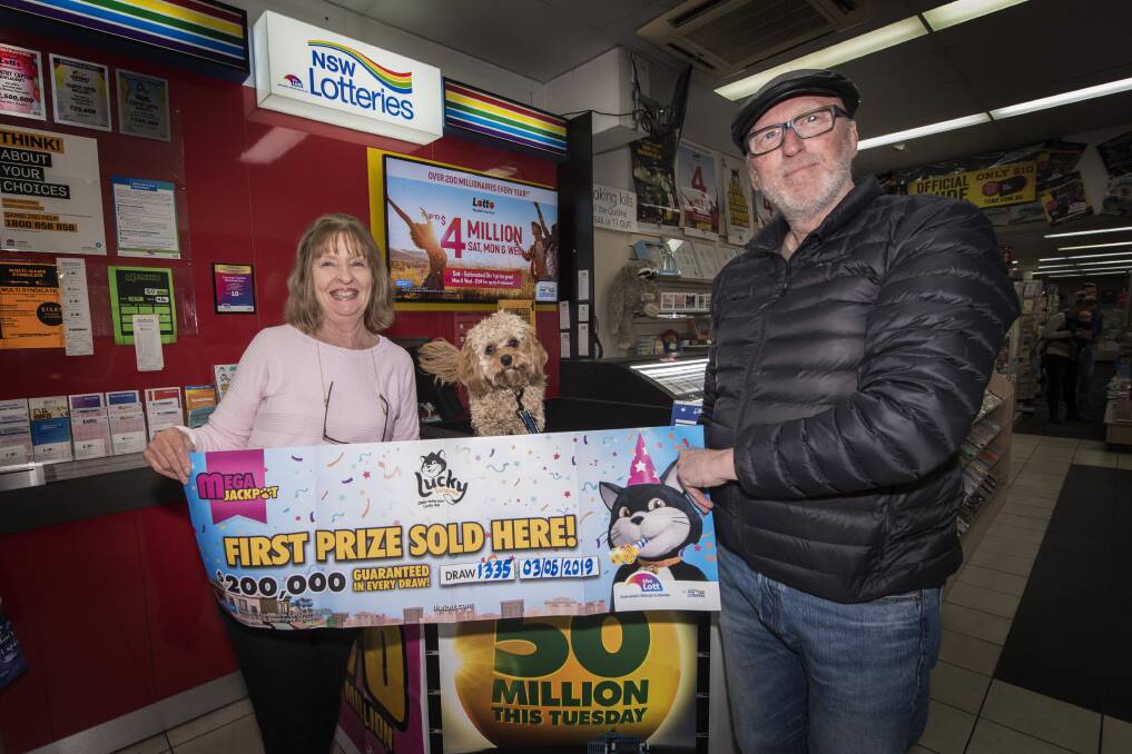 TOP DOG: Country Capital newsagency owners Jenny and Glenn Andrews and their prized pooch Billy touting their latest winning lotto ticket. Photo: Peter Hardin 050619PHE010