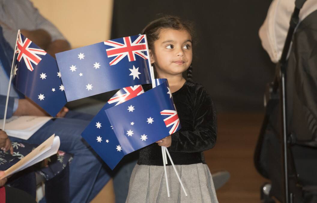 FLAG DAY: A youngster rounds up a number of flags at Tamworth's most recent citizenship ceremony. Photo: Peter Hardin 170919PHA024