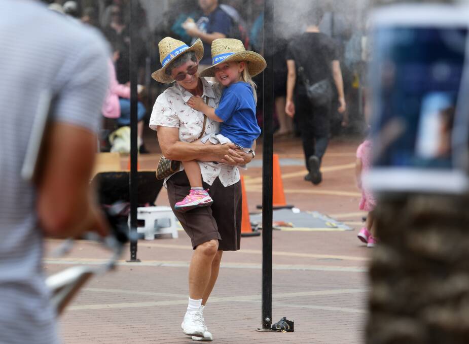 COOL CREW: This pair grabbed a bit of relief under the mist jets on Fitzroy Street which proved to be very popular in the heat of festival. Photo: Gareth Gardner 220119GGB11