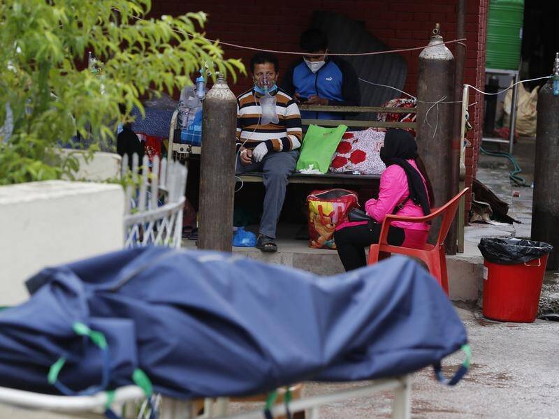 A patient receives oxygen as the body of a COVID-19 victim lies outside a hospital in Kathmandu.