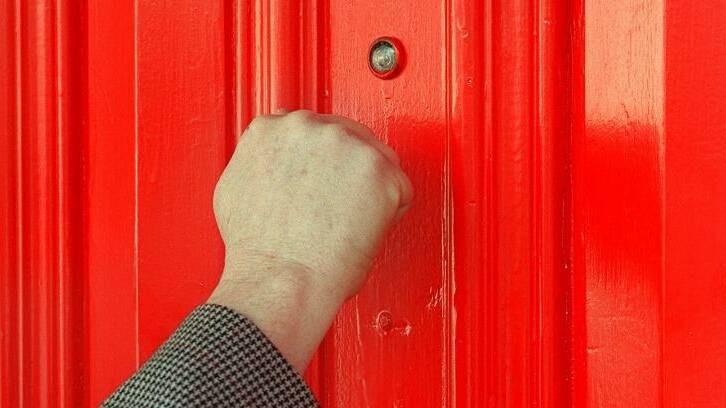 A hand knocking on a door. Picture is from file