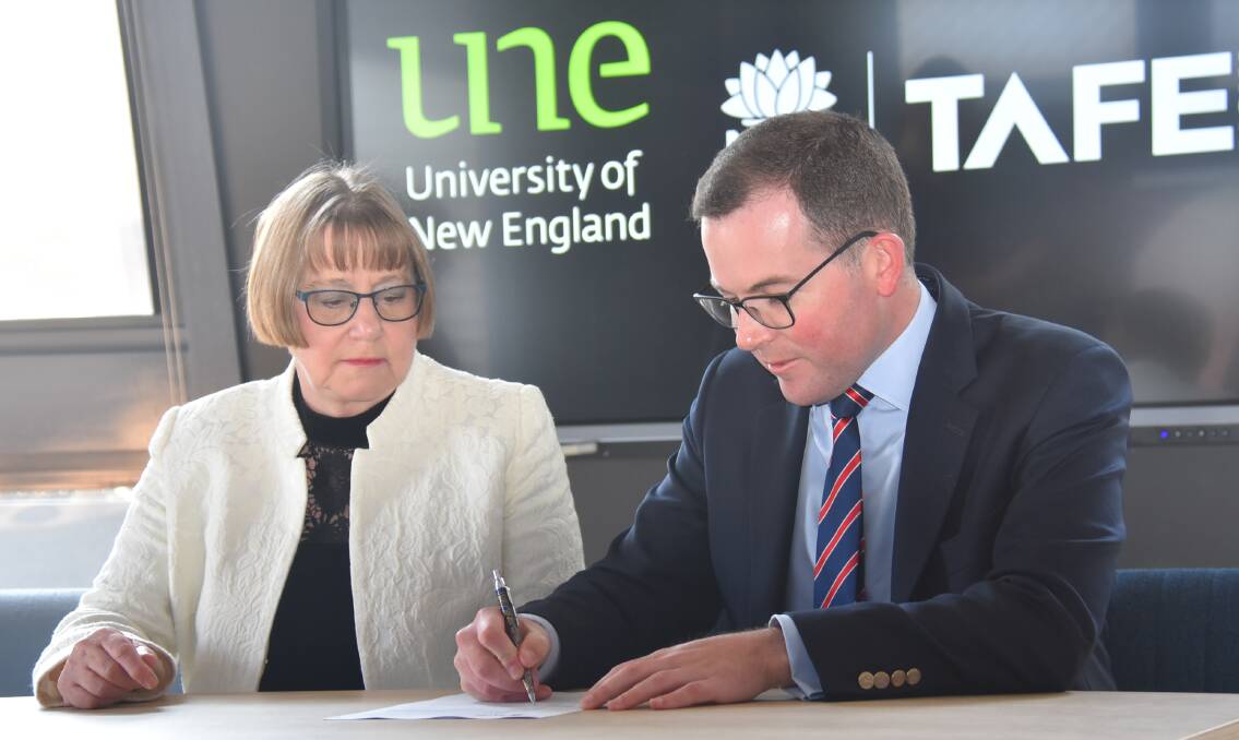 Vice-chancellor of UNE Anabelle Duncan and Member for Northern Tablelands Adam Marshall sign the agreement that will see collaborations between the two institutions.