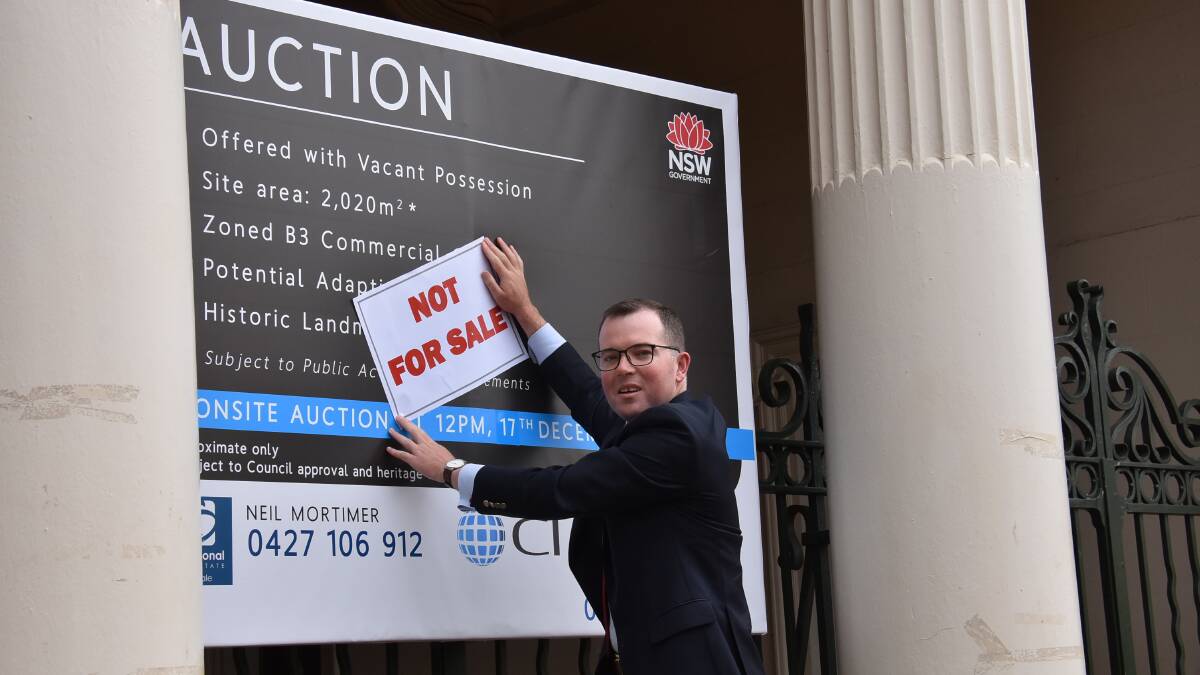 OFF THE MARKET: Member for Northern Tablelands puts up his "not for sale" sign on Armidale's first courthouse, built in 1860.
