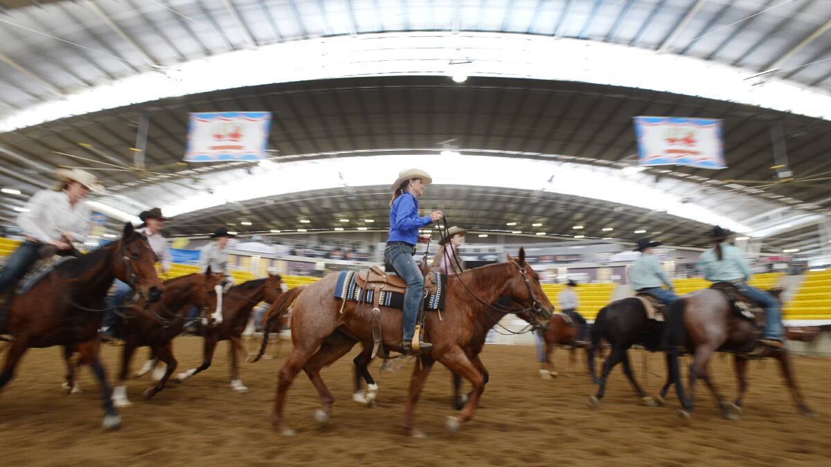 EQUINE ACTION: One of the Victorian contingent, Zannie Randell from Benalla (in the blue shirt), warms up for her event at AELEC. Photo: Barry Smith 280514BSB06