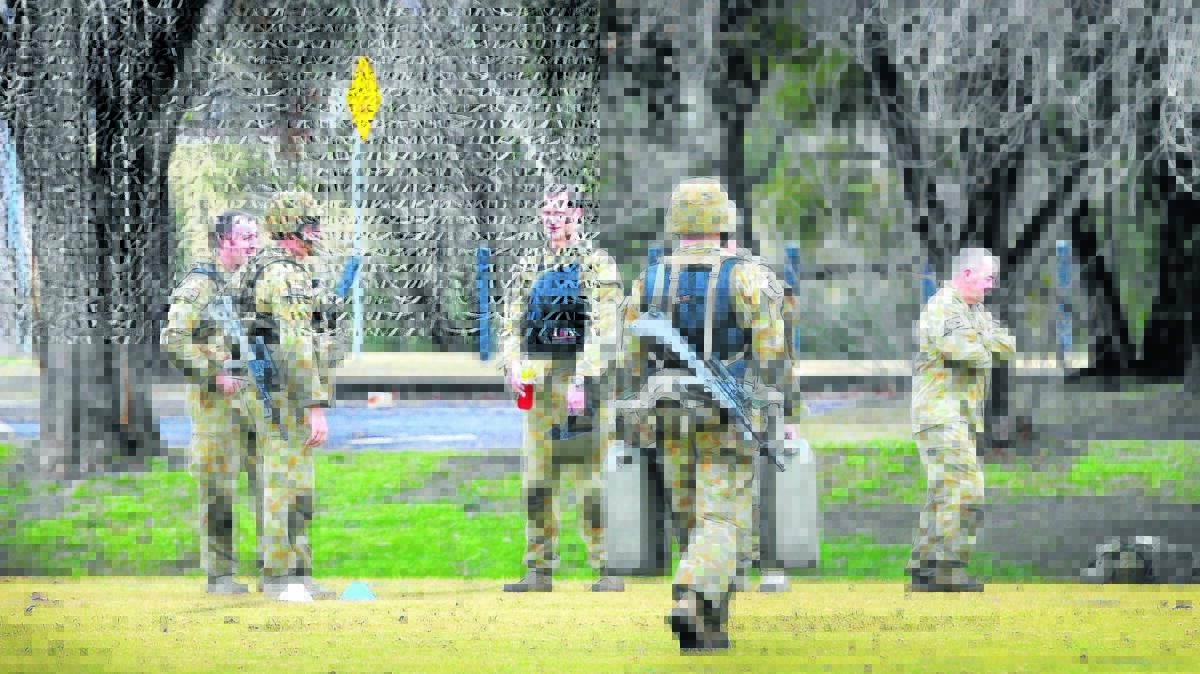 ALERT, NOT ALARMED: Members of the 12th/16th Hunter River Lancers complete testing with webbing and weapons, carrying jerry cans at Gipps St fields. Photo: Gareth Gardner 160714GGB02