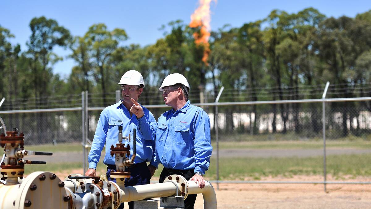 ON TRACK: Santos operation engineer team leader Todd Dunn and Santos NSW general manager Peter Mitchley discuss the narrabri Gas Project as flaring goes on behind them at the Bibblewindi site in the Pilliga Scrub.