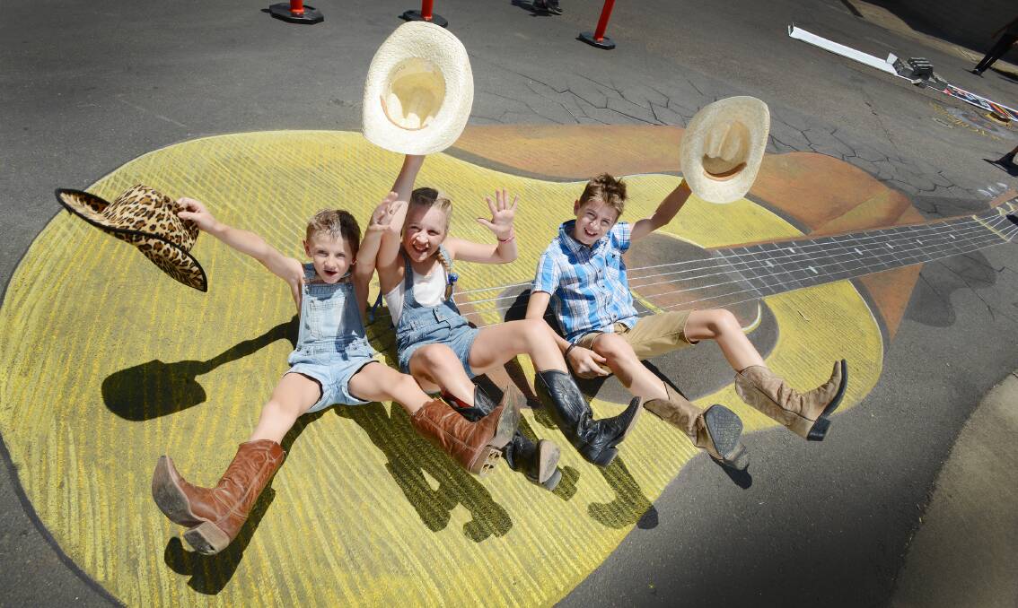 BIG GUITAR: Tamworth kids Cooper, 7, Chloe, 10, and Jake Darlington made merry with some groundbreaking guitar work in Country Music Capital. Photo: Barry Smith 190115BSE03